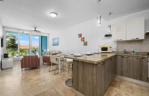 Boegoeroei Condominio | Gated community with resort-style amenities - 2 bedroom, 2 bath with an open concept living room and kitchen. Private balcony overlooks pool area.