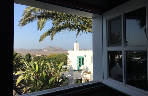 Teguise Casa | Oasis verde con piscina y vista a las montañas de fuego.