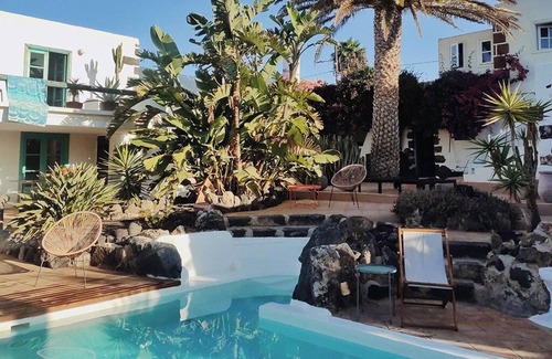 Teguise Casa | Oasis verde con piscina y vista a las montañas de fuego.