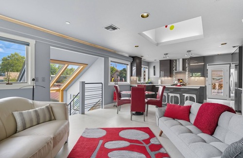 Hough Apartamento | Top-level duplex featuring a sleek open concept kitchen with stainless appliances, cozy fireplace, stylish furnishings, and in-unit washer/dryer. Designed for basking in the sun under skylights in thoughtful details throughout.