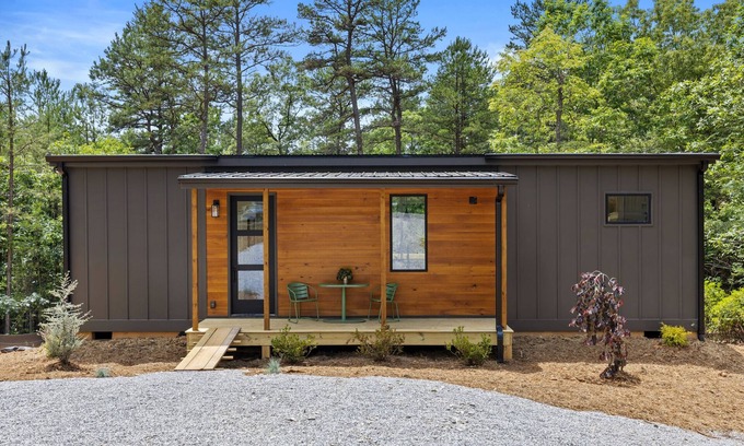 Young Harris Apartamento | Enjoy treetop views in a 2BR/1BA tiny home nestled in the North Georgia mountains. Whip up meals in the chef’s kitchen, cozy up by the wood-burning stove, unplug in the spa-style shower, relax on your private deck, and cool off in the community pool.