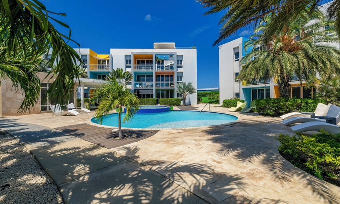 Boegoeroei Condominio | Gated community with resort-style amenities - 2 bedroom, 2 bath with an open concept living room and kitchen. Private balcony overlooks pool area.