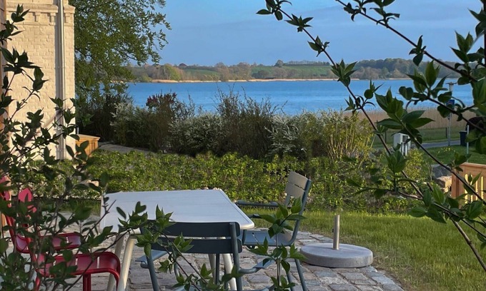 Ulsnis Casa | Newly built wooden house "Remise am Fährhaus" with unique architecture directly on the Schlei with jetty and bathing area for your well-deserved vacation in an absolute feel-good atmosphere, with a huge garden area and old trees